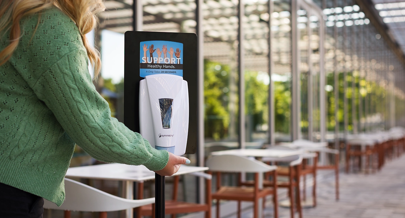 Woman using an Empathy Mavrik Symmetry dispenser with Bmod in a public cafeteria setting