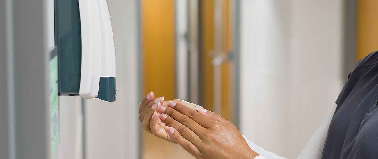 Hands using an Altra dispenser on the wall